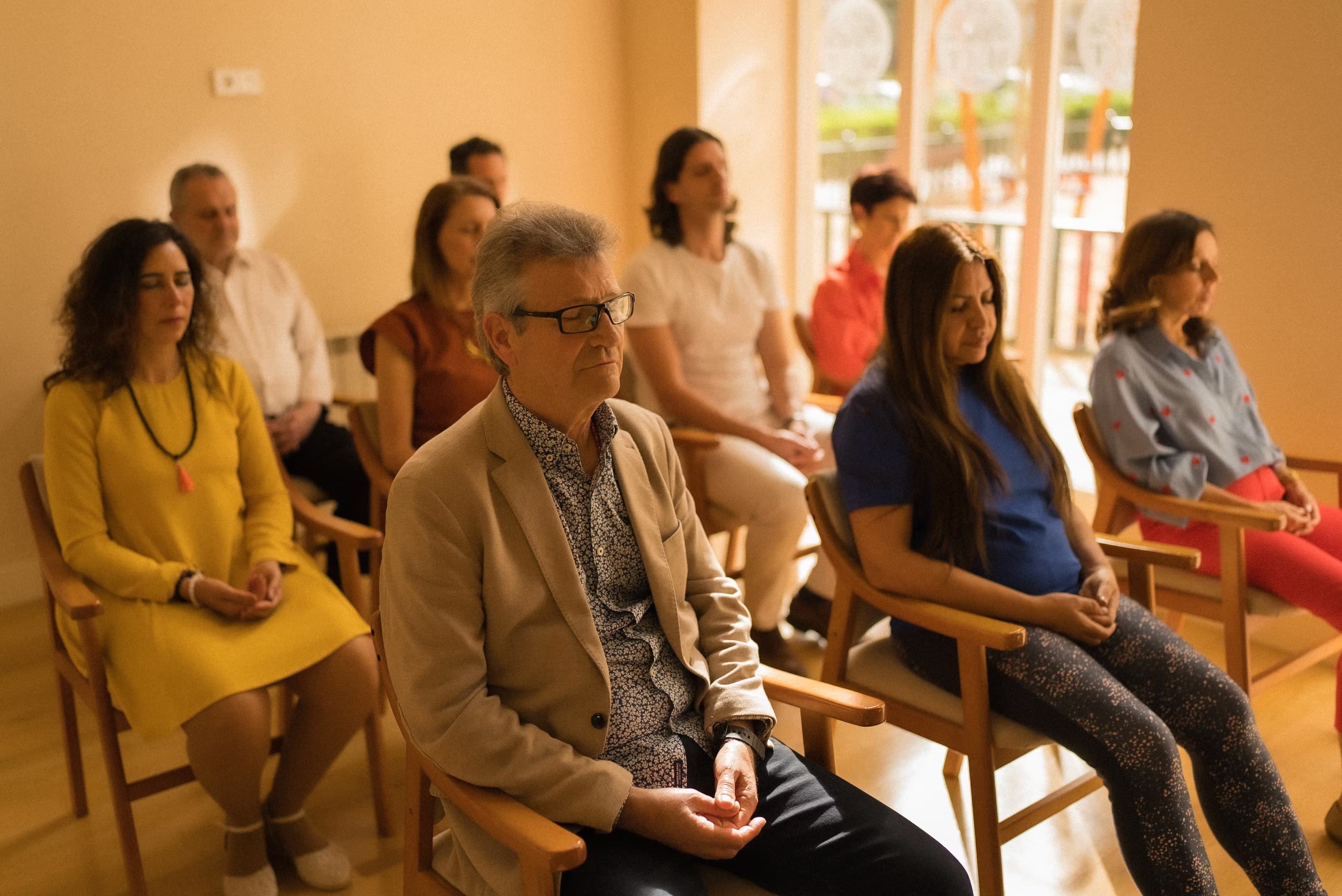 Persone che praticano la meditazione trascendentale, sedute con gli occhi chiusi.